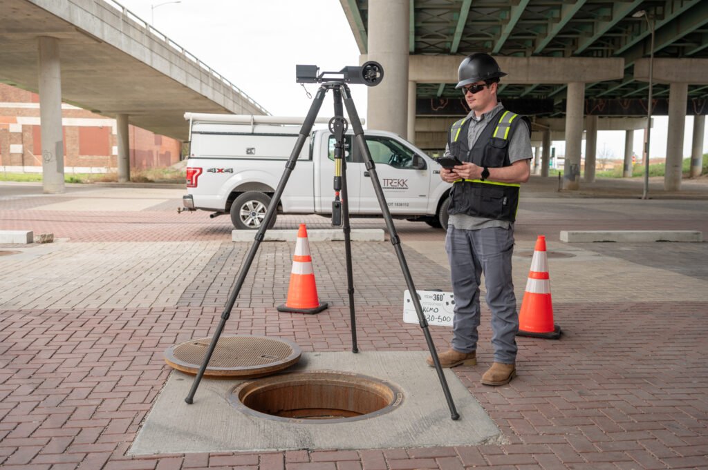 Operator using TREKK360 at a street manhole with a work truck behind