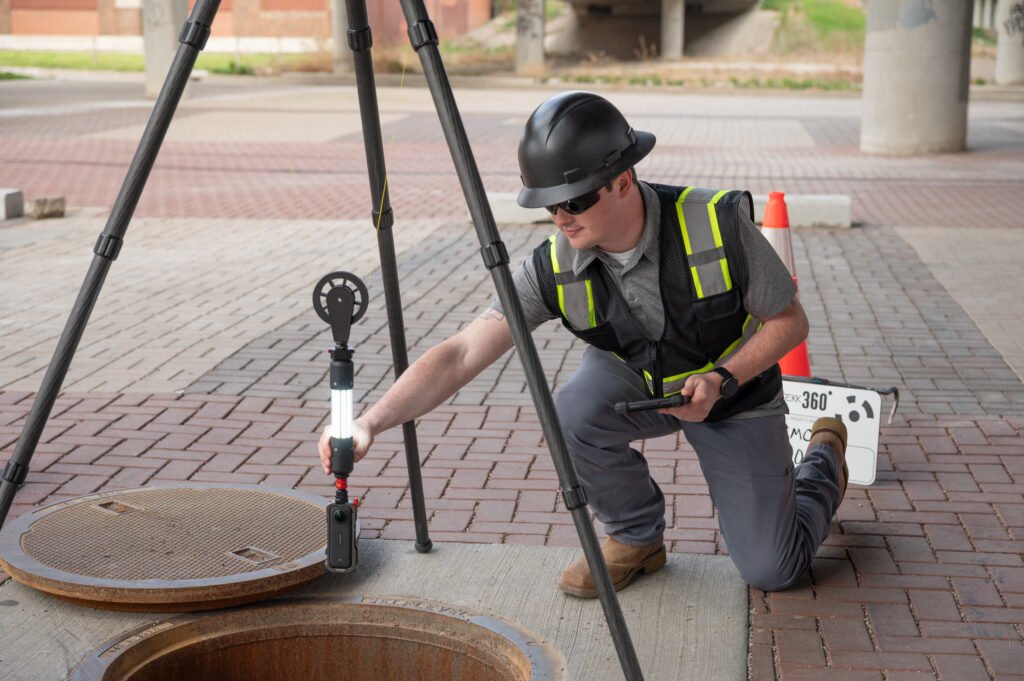 Operator lowering the TREKK360 camera into an open manhole