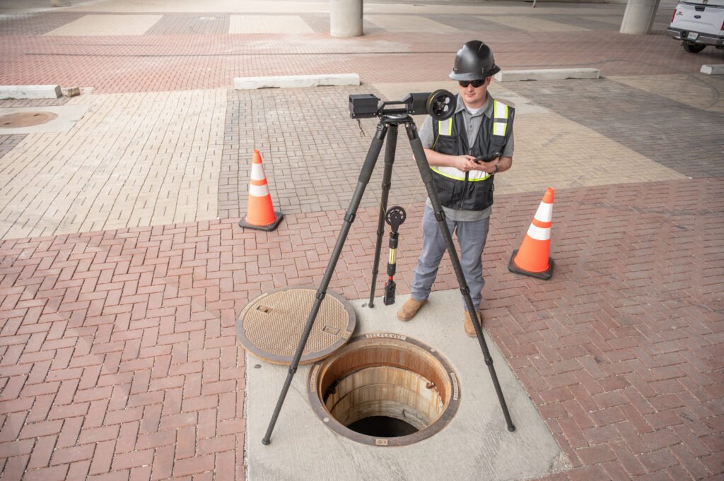 TREKK360 operator at an open manhole with traffic cones