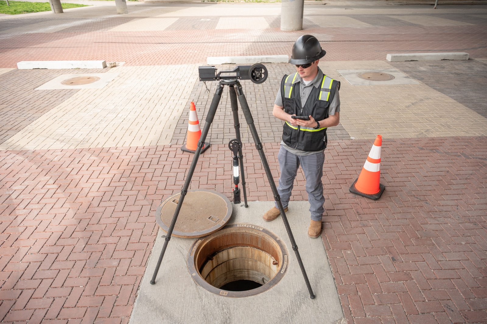 TREKK360 operator standing over a manhole with the tripod